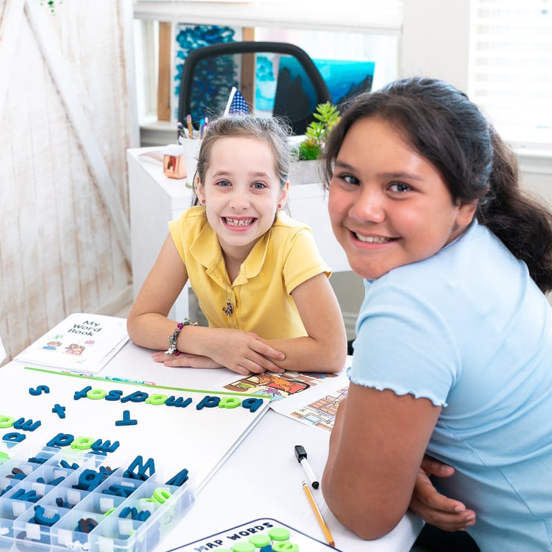two school-aged students during a lesson involving mapping out letters and words